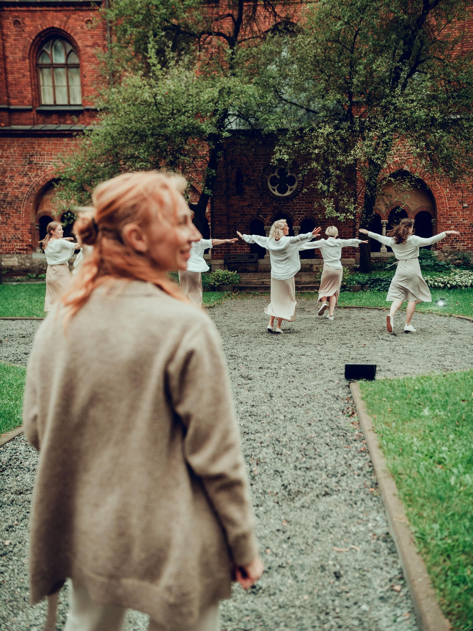 Dance Teacher Leading Choreography at Outdoor Performance Photo of a dance teacher leading students through a choreographed performance outdoors, demonstrating movement and artistic expression.